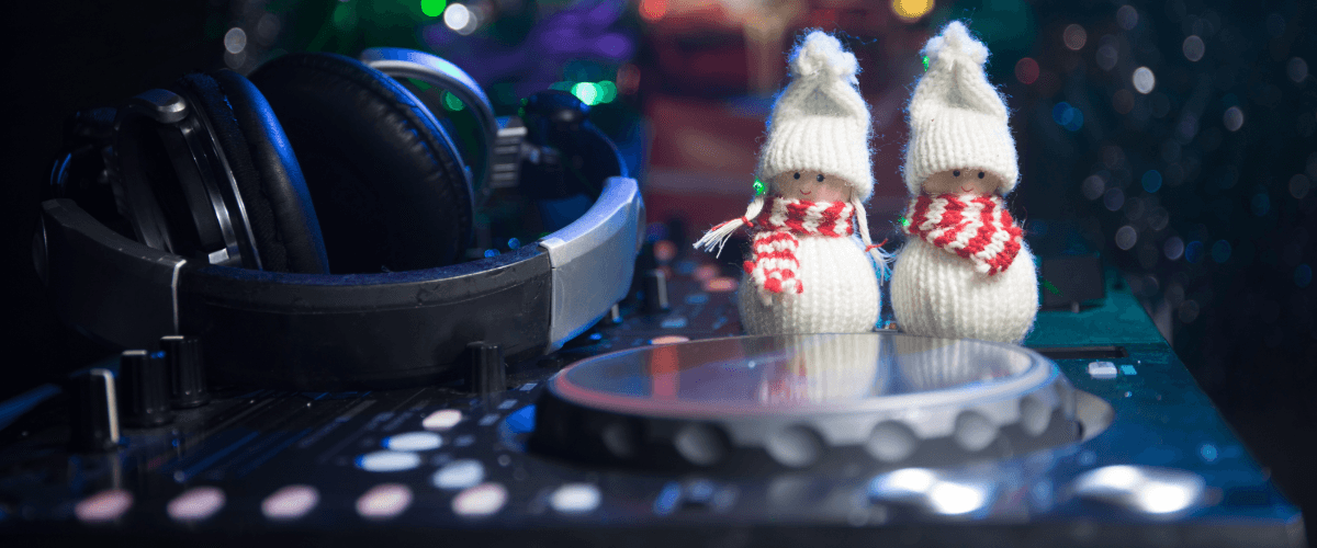 headphones and a DJ deck with two cute little white decorative snowmen on them. A Christmas tree is in the background